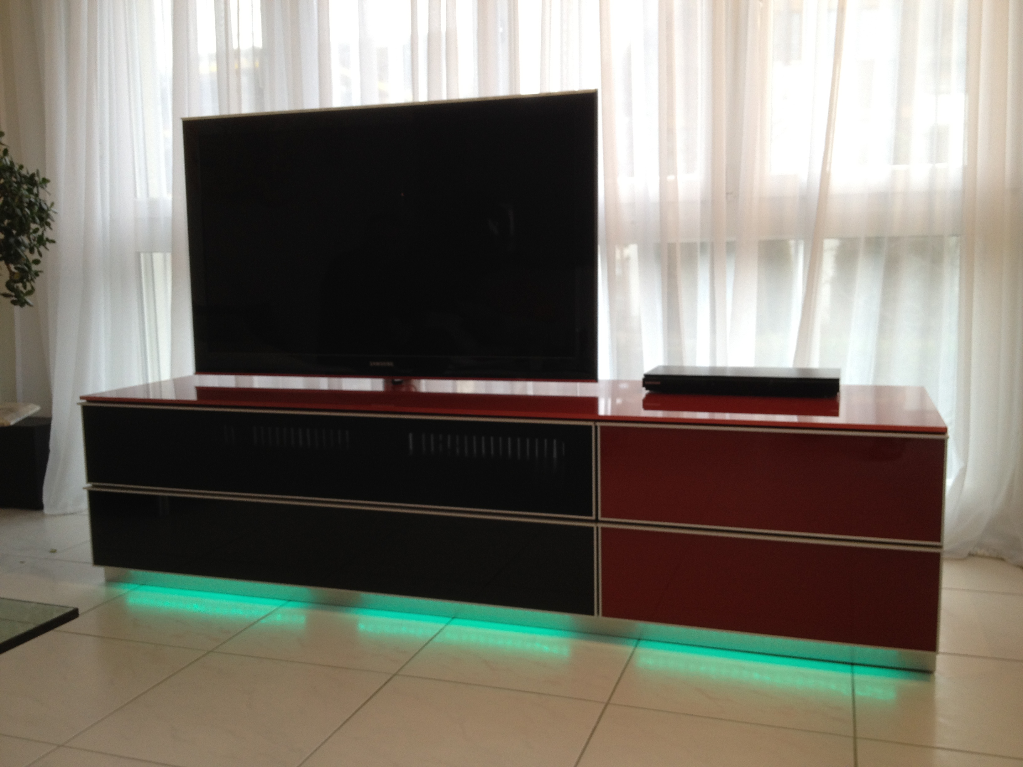 Ausgeschalteter  TV im Wohnzimmer mit grünem Licht am TV-Möbel